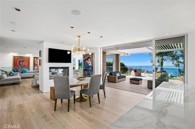 dining space featuring an inviting chandelier, a wall of windows, and light hardwood / wood-style flooring