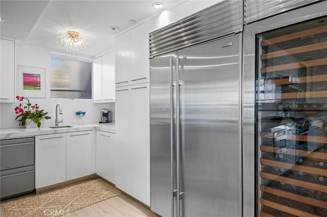 kitchen with white cabinets, beverage cooler, sink, and stainless steel appliances