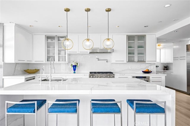 kitchen with decorative light fixtures, sink, white cabinetry, and light stone countertops