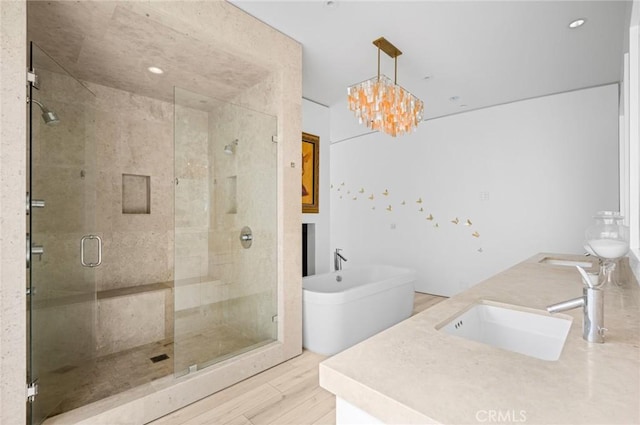 bathroom featuring wood-type flooring, vanity, an inviting chandelier, and plus walk in shower