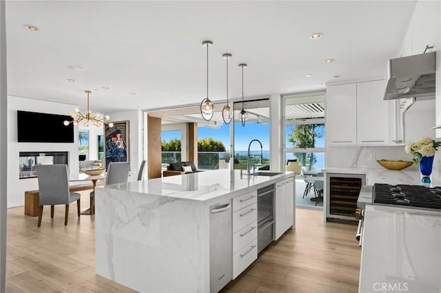 kitchen featuring sink, white cabinets, a center island with sink, and wine cooler