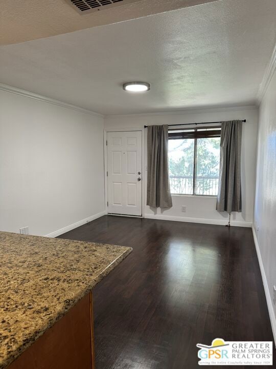 empty room with dark wood-type flooring and ornamental molding