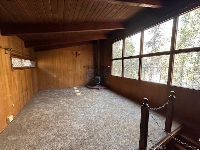 unfurnished sunroom with beamed ceiling, a wood stove, and a healthy amount of sunlight