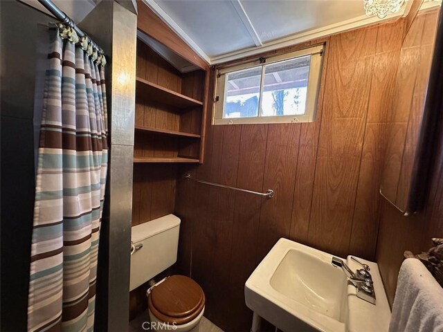 full bath with a shower with curtain, toilet, wooden walls, and a sink