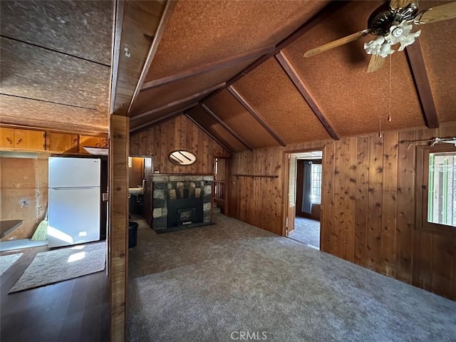 bonus room featuring lofted ceiling, ceiling fan, a fireplace, wood walls, and carpet flooring