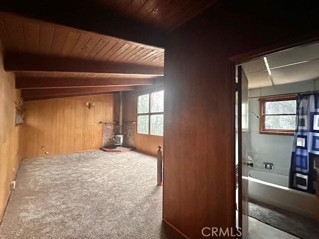 bonus room with beamed ceiling, wood ceiling, wood walls, and a wood stove