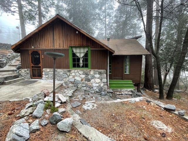 rustic home with stone siding and a patio area