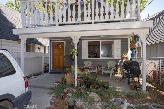 view of exterior entry featuring a balcony and a patio