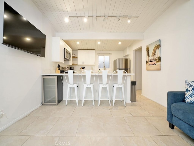 kitchen featuring white cabinets, stainless steel appliances, rail lighting, kitchen peninsula, and a breakfast bar area