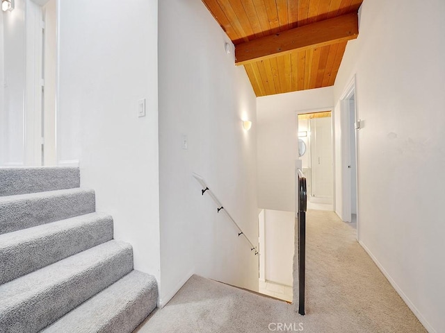 staircase featuring carpet, beamed ceiling, and wooden ceiling