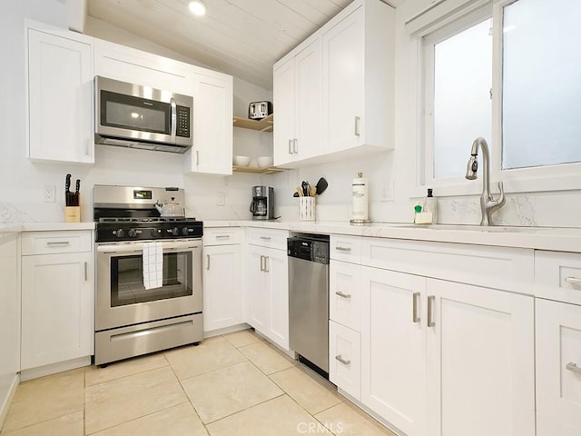 kitchen with light tile patterned flooring, stainless steel appliances, white cabinetry, and sink