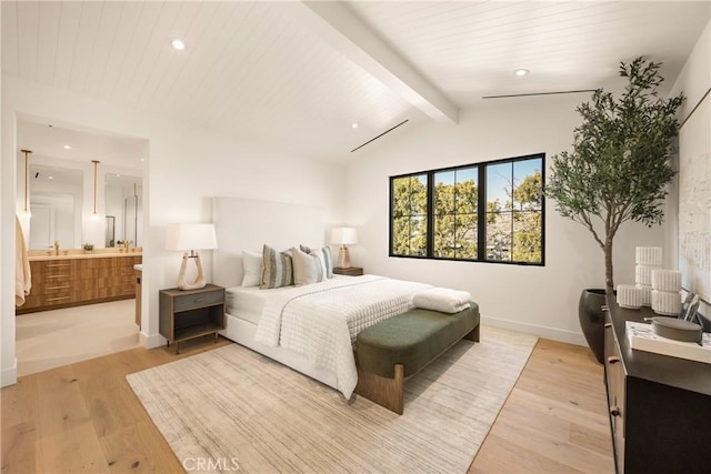 bedroom featuring lofted ceiling with beams, ensuite bathroom, and light wood-type flooring