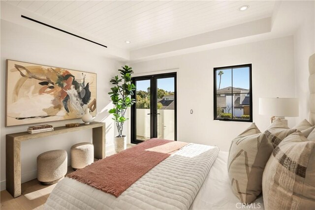 bedroom with wood ceiling, a raised ceiling, light wood-type flooring, and access to outside