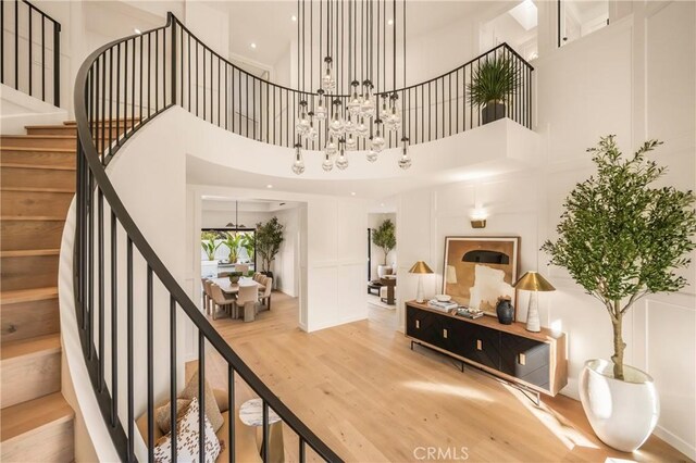 interior space with hardwood / wood-style flooring, a towering ceiling, and a notable chandelier