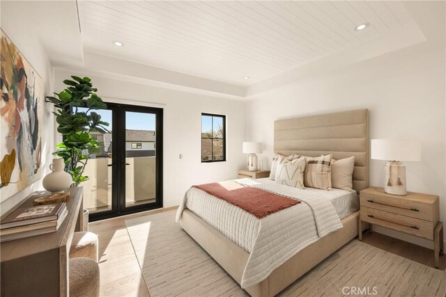 bedroom with wood ceiling, a raised ceiling, and light wood-type flooring