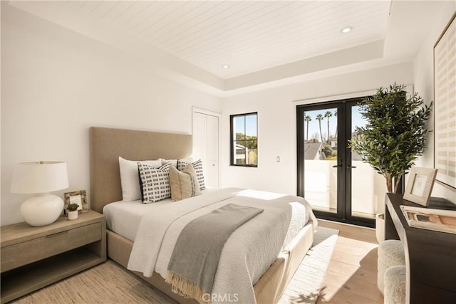 bedroom featuring french doors, wood ceiling, access to outside, a raised ceiling, and light hardwood / wood-style floors