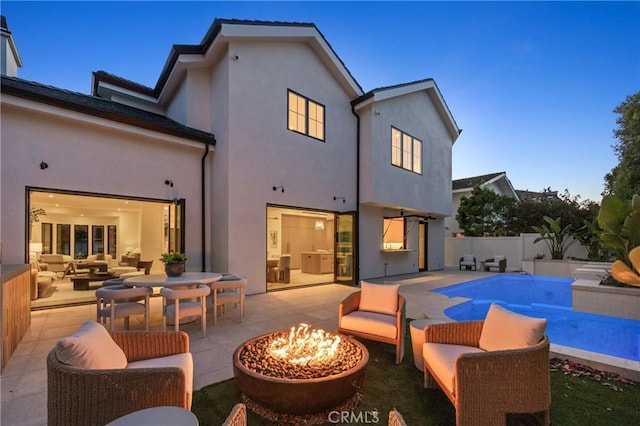 rear view of property with a fenced in pool, a patio area, and an outdoor living space with a fire pit