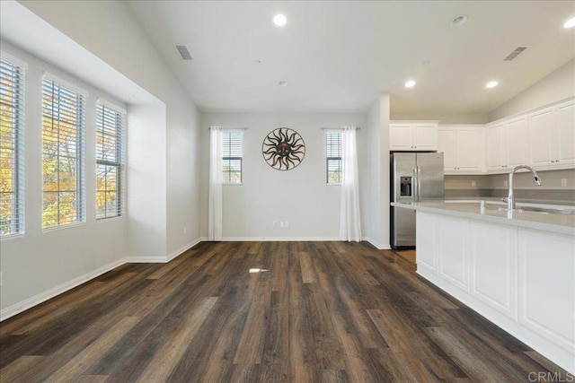 kitchen with white cabinetry, stainless steel fridge, dark hardwood / wood-style flooring, lofted ceiling, and sink