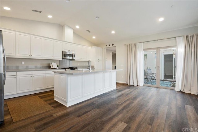 kitchen featuring lofted ceiling, a center island with sink, white cabinetry, stainless steel appliances, and dark hardwood / wood-style flooring