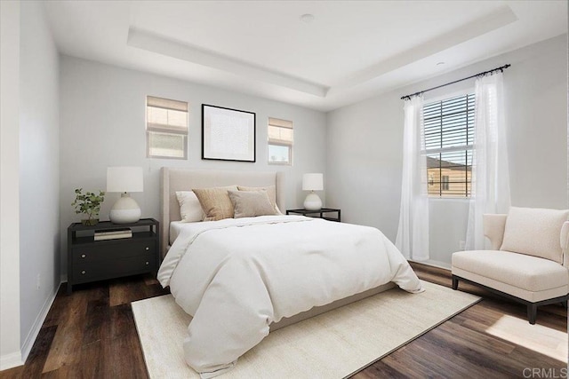 bedroom with a tray ceiling and dark hardwood / wood-style floors