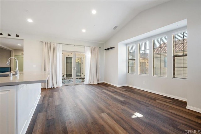 unfurnished living room featuring sink, dark hardwood / wood-style flooring, lofted ceiling, and french doors