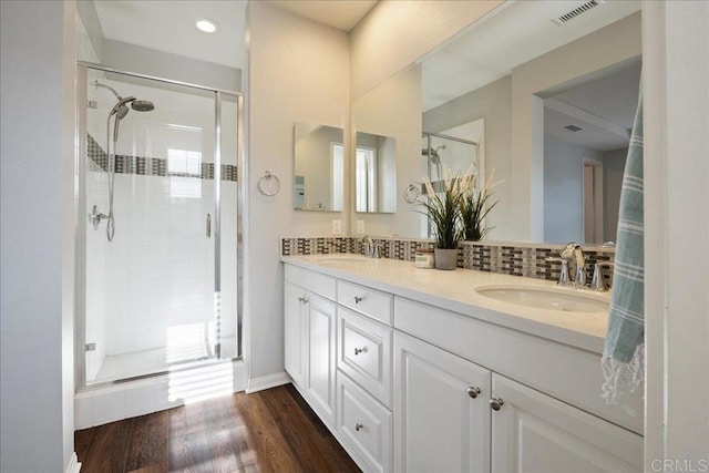 bathroom with tasteful backsplash, walk in shower, hardwood / wood-style floors, and vanity