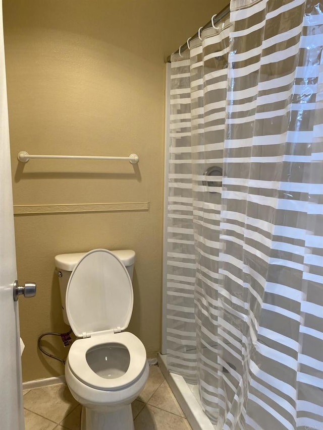 bathroom with tile patterned floors, toilet, and a shower with curtain