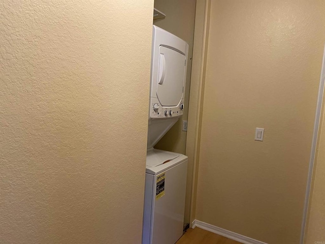 clothes washing area featuring hardwood / wood-style floors and stacked washer / drying machine