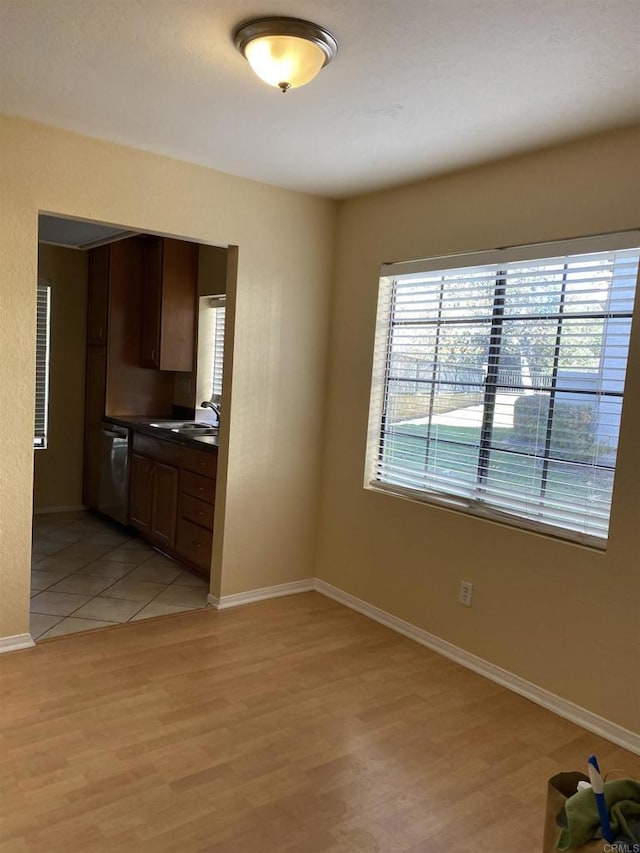 kitchen with dark brown cabinets, dishwasher, sink, and light hardwood / wood-style flooring