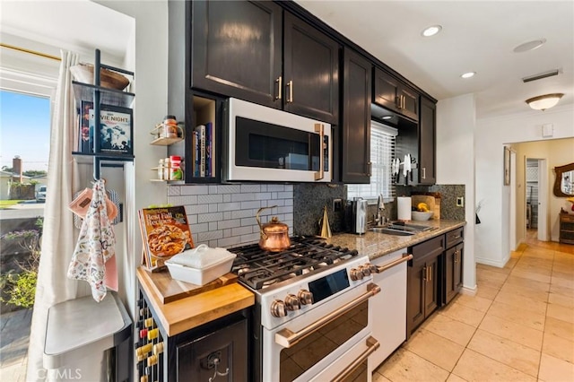 kitchen featuring double oven range, backsplash, light tile patterned flooring, dishwasher, and sink