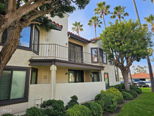 view of home's exterior featuring a fenced front yard, stucco siding, a tile roof, and a balcony