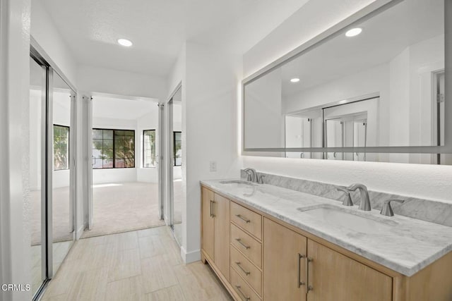 bathroom featuring double vanity, recessed lighting, baseboards, and a sink