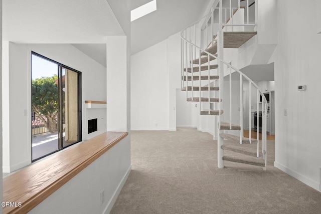 stairway with carpet flooring, a fireplace with raised hearth, and baseboards