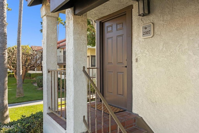 doorway to property with a yard and stucco siding