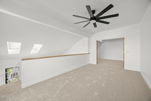 additional living space with vaulted ceiling with skylight, baseboards, and carpet floors