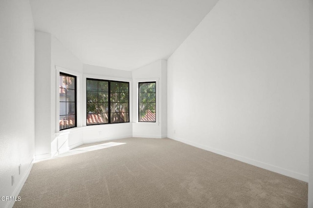 carpeted empty room with baseboards and lofted ceiling