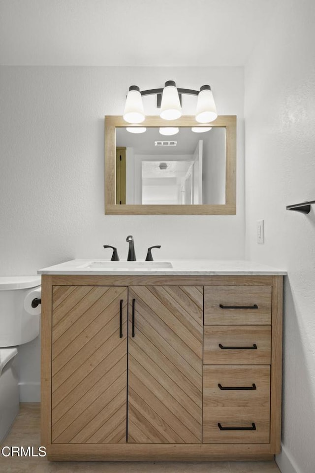 bathroom featuring visible vents, toilet, vanity, and baseboards