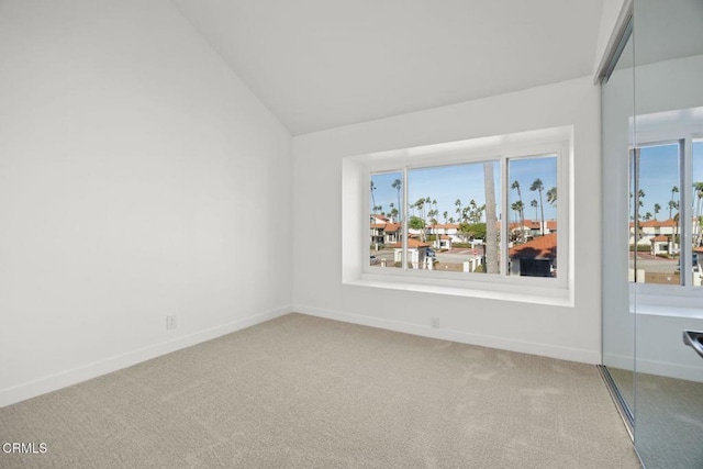 empty room featuring a wealth of natural light, baseboards, carpet, and vaulted ceiling