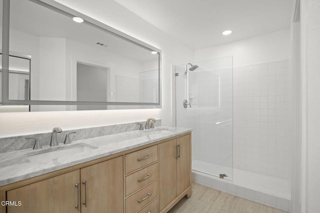 bathroom with double vanity, recessed lighting, walk in shower, and a sink