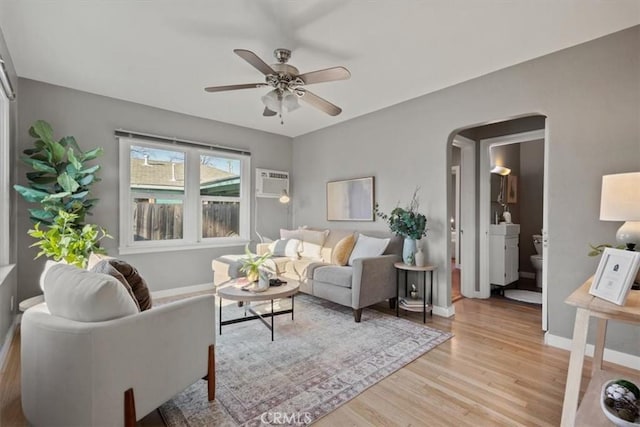 living room with ceiling fan, a wall mounted air conditioner, and light wood-type flooring