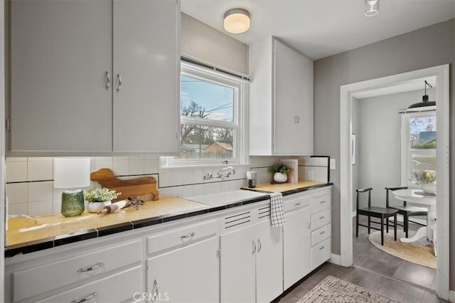 kitchen with tasteful backsplash, sink, tile countertops, and white cabinetry