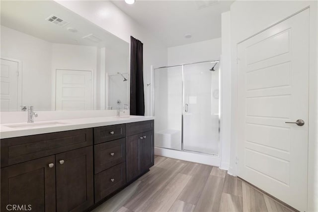 bathroom featuring wood-type flooring, walk in shower, and vanity