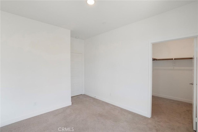 unfurnished bedroom with a spacious closet, light colored carpet, and a closet