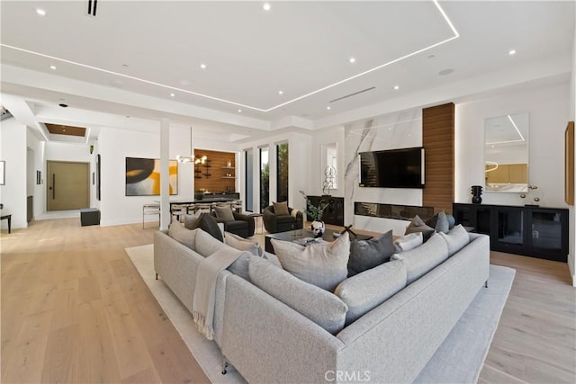 living room featuring an inviting chandelier, light hardwood / wood-style floors, and a tray ceiling