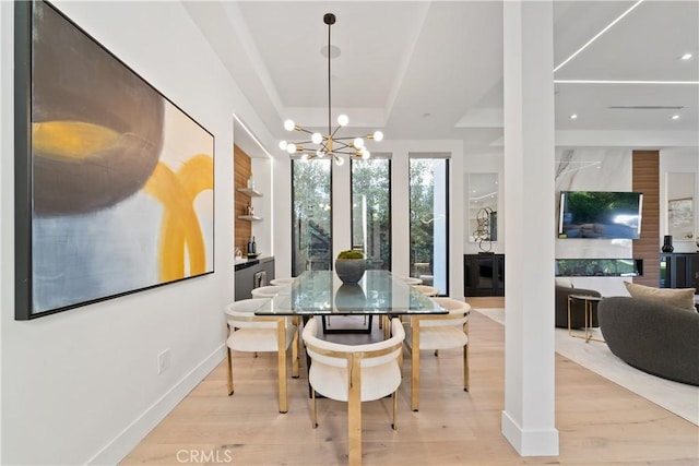 dining area with light hardwood / wood-style flooring, a tray ceiling, and a notable chandelier