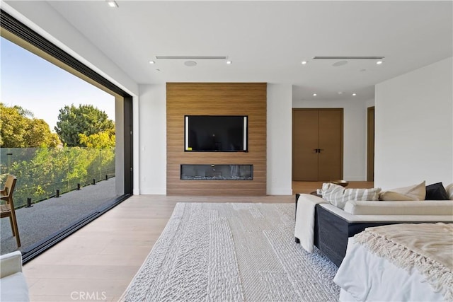 bedroom featuring light wood-type flooring, access to exterior, and a fireplace