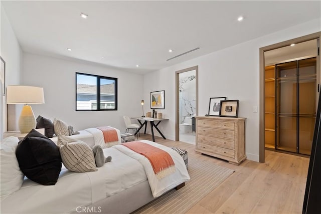 bedroom featuring connected bathroom and light wood-type flooring