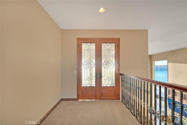 entryway featuring light colored carpet, a water view, and french doors