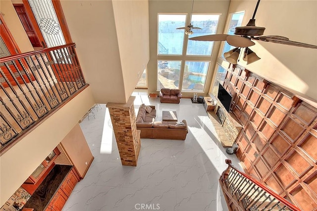 27008 Reef Ln, Helendale, CA 92342 - living area featuring a ceiling fan, marble tiled flooring, a fireplace with raised hearth, plenty of natural light, and a high ceiling