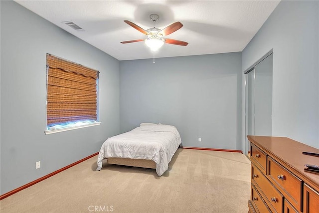 bedroom with ceiling fan, a closet, and light colored carpet